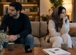 دختر و پسر جوان با حالت ناراحتی و فاصله نشسته روی کاناپه با جعبه حلقه ازدواج روی میز به عنوان نماد اختلاف قبل از ازدواج